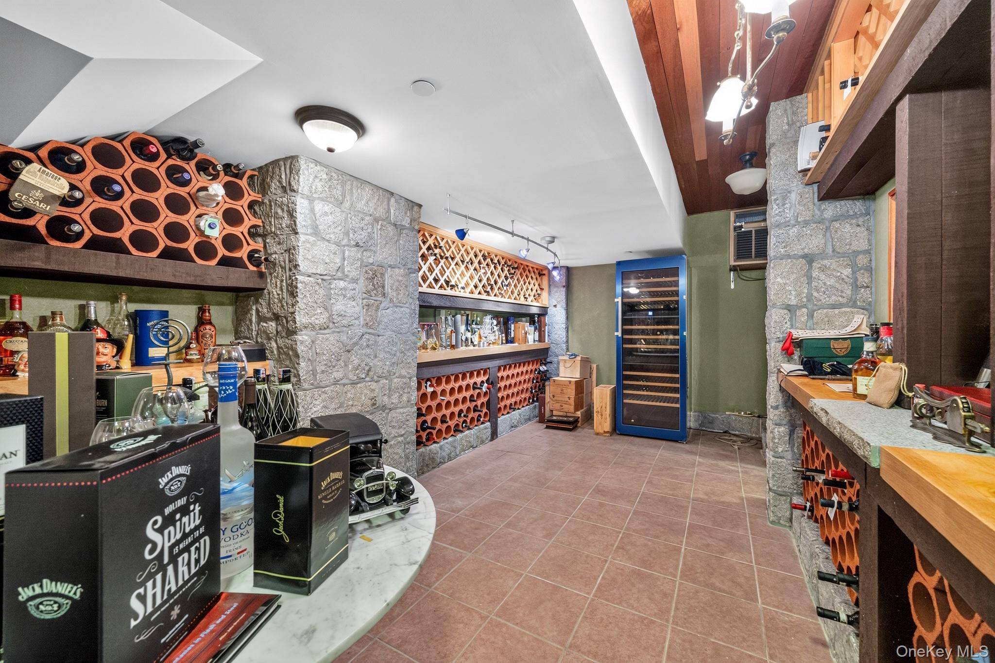 23 Inningwood Road Ossining, NY 10562 - Photo 34 of 50 Dedicated wine storage room featuring extensive terracotta and wood-finish bottle racks, stone accent walls, a built-in bar area with a solid surface countertop, and tiled flooring