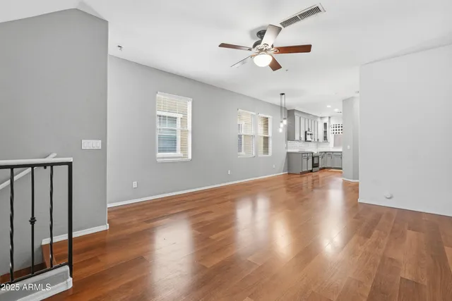 a view of empty room with wooden floor and fan