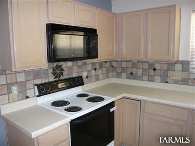 7828 South Lauder Street Tucson, AZ 85747 - Photo 4 of 11 a kitchen with a sink a stove and white cabinets