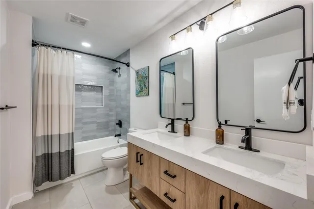 a bathroom with a double vanity sink toilet mirror and shower