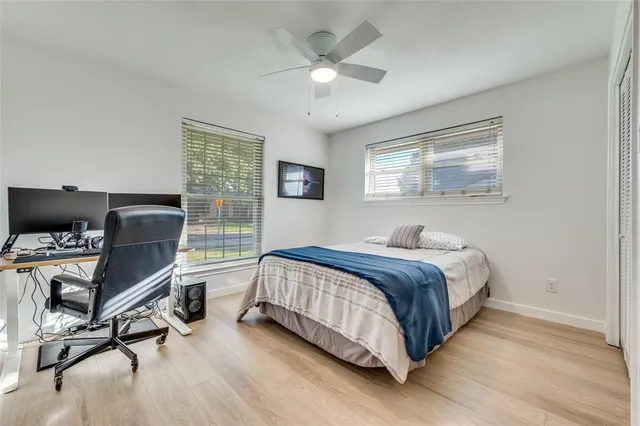 a bedroom with a bed a computer on a desk and chair