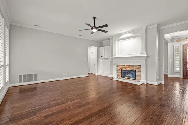 a view of an empty room with wooden floor fireplace and a window