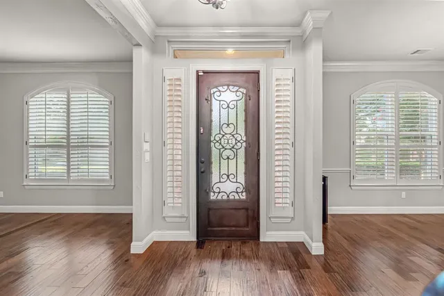 an empty room with wooden floor a mirror and windows