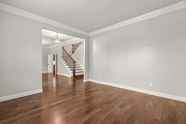 a view of an empty room with wooden floor and stairs