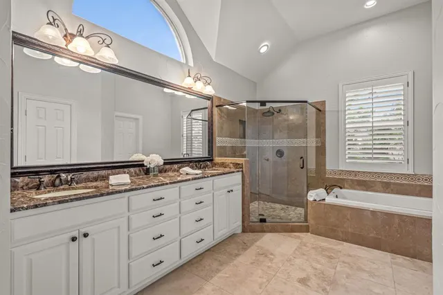 a spacious bathroom with double sink a a mirror a bathtub and shower