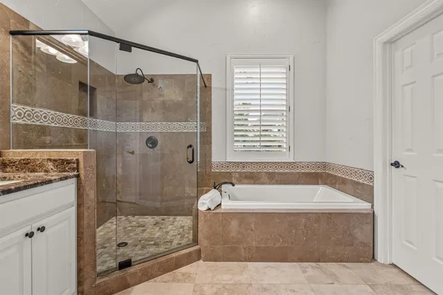 a spacious bathroom with a granite countertop tub shower and mirror