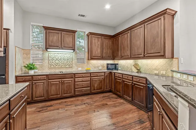 a kitchen with stainless steel appliances granite countertop wooden cabinets a stove top oven a sink and dishwasher with wooden floor