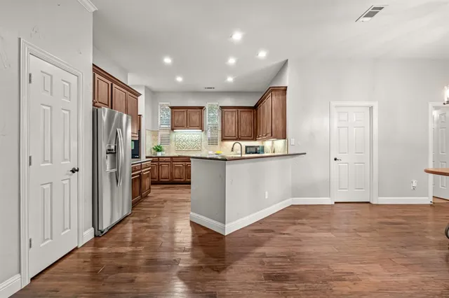 a kitchen with stainless steel appliances kitchen island granite countertop a refrigerator and a stove top oven