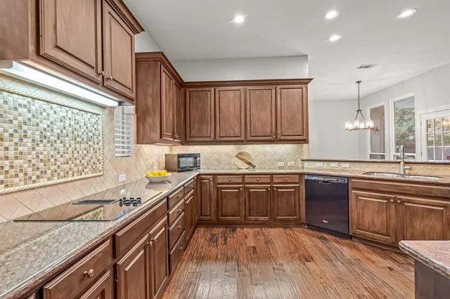 a kitchen with stainless steel appliances granite countertop wooden cabinets a sink dishwasher a stove and a refrigerator