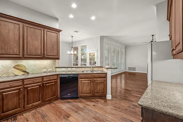 a kitchen with stainless steel appliances granite countertop wooden cabinets a sink a stove a dining table and chairs