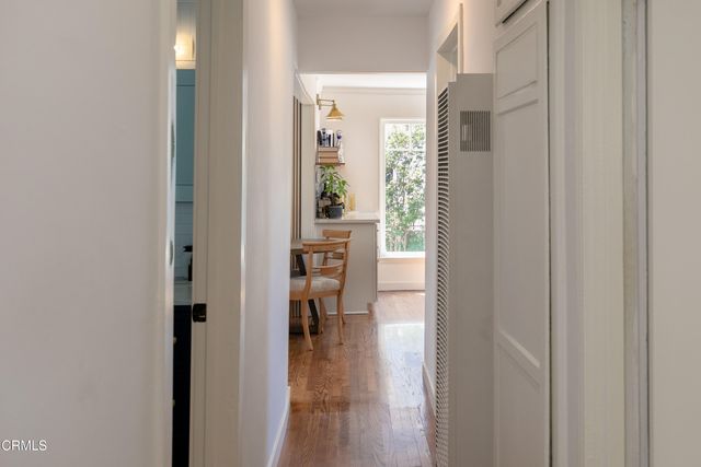 a view of a hallway with wooden floor and a bathroom