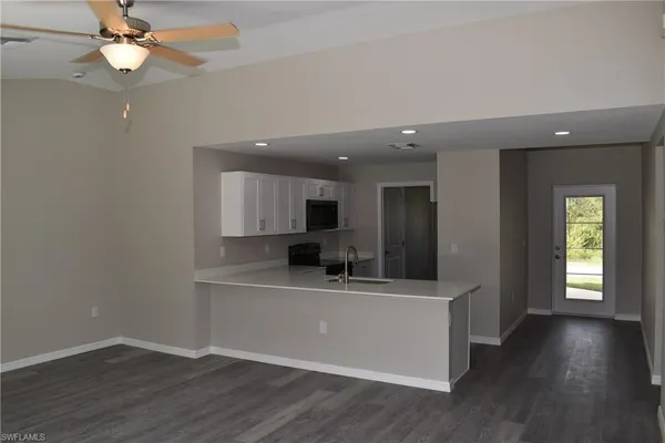 a view of a kitchen with a sink dishwasher and microwave with wooden floor