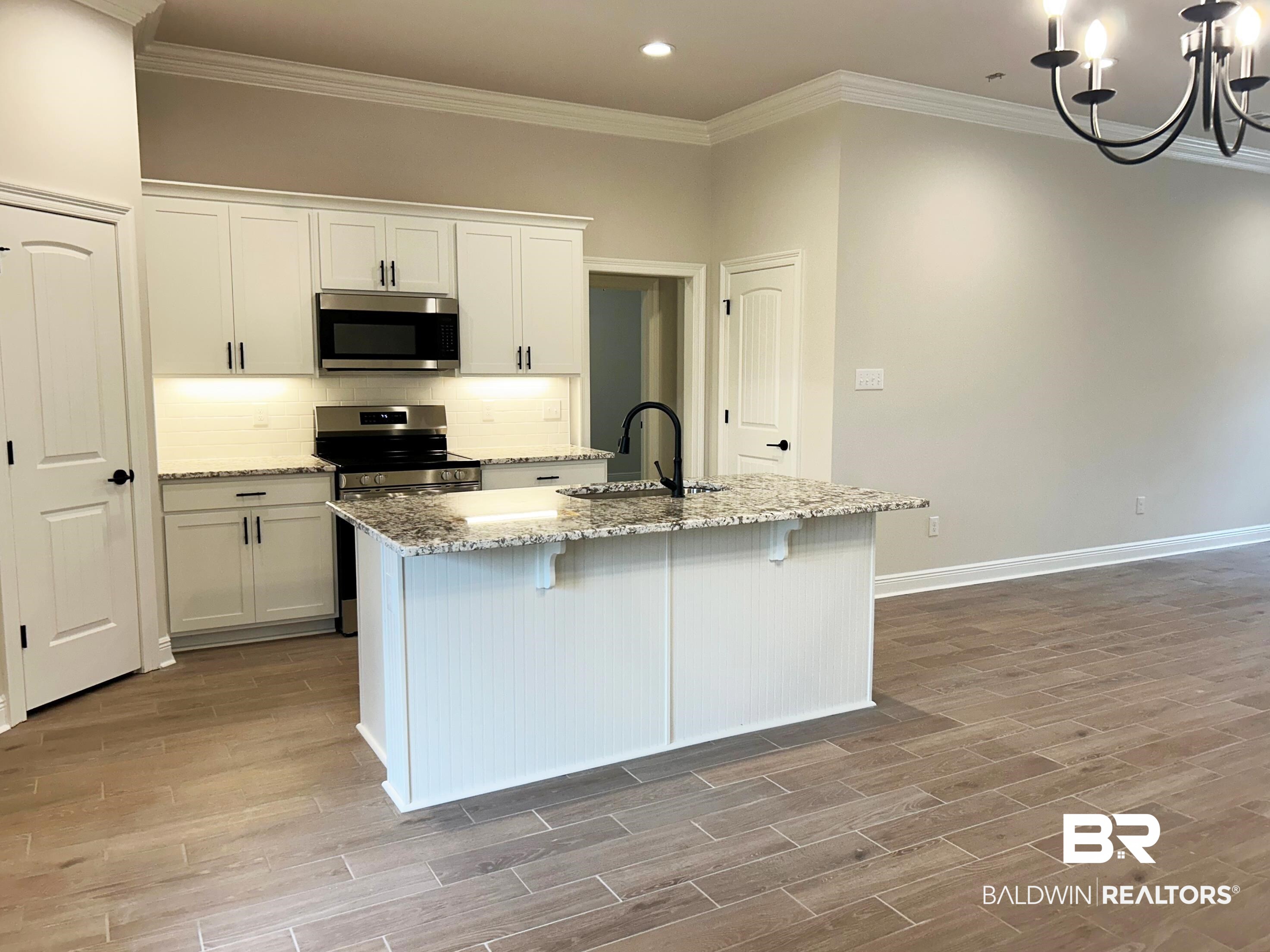873 Sumter Loop Foley, AL 36535 - Photo 7 of 26 Kitchen featuring decorative backsplash, light stone counters, ornamental molding, white cabinetry, and stainless steel appliances