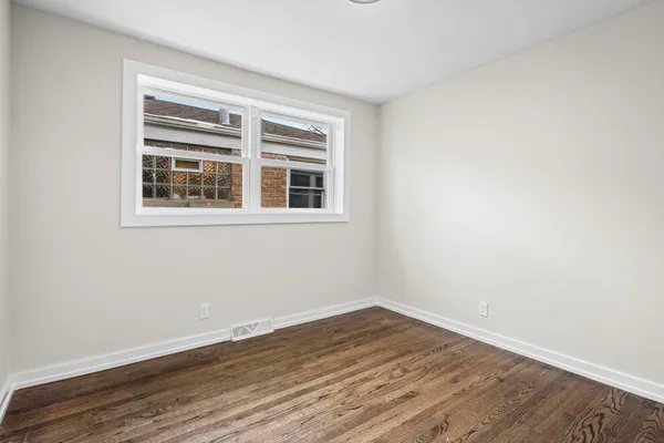 a view of empty room with wooden floor and windows