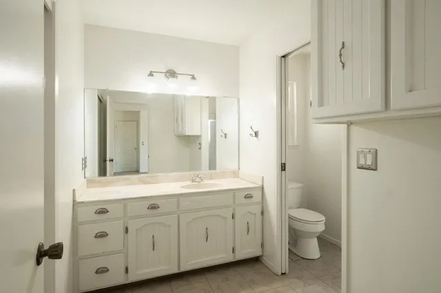 a spacious bathroom with a granite countertop sink a toilet and a mirror