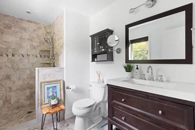 a bathroom with a toilet a sink a mirror and a window