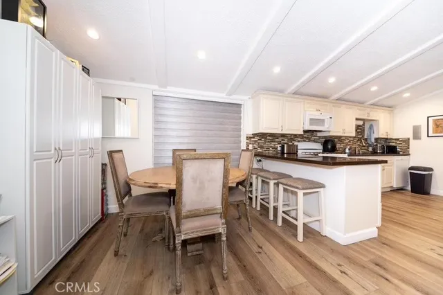 a kitchen with stainless steel appliances granite countertop a stove top oven a sink dishwasher a dining table and chairs with wooden floor