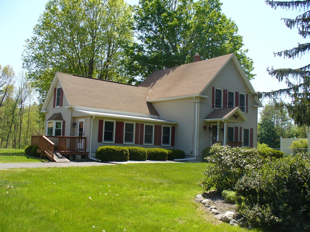 a front view of a house with a garden and trees