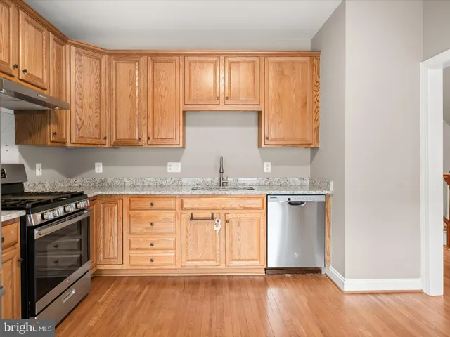 a kitchen with granite countertop wooden cabinets stainless steel appliances and a window