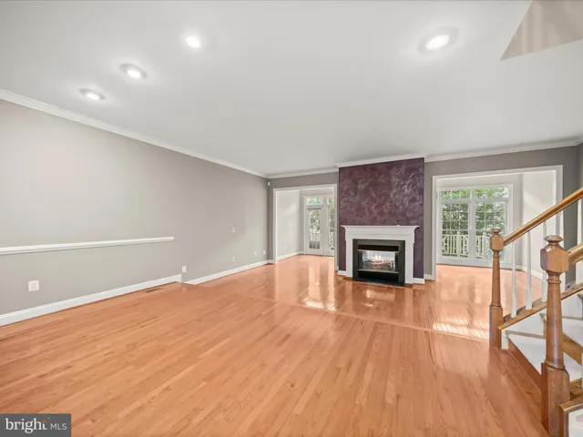 a view of an empty room with wooden floor fireplace and a window