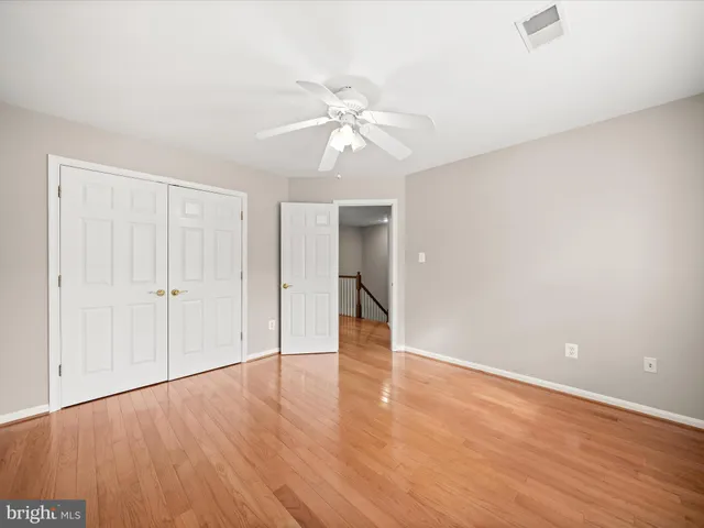 an empty room with wooden floor closet and windows