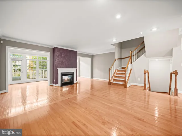a view of an empty room with wooden floor fireplace and a window
