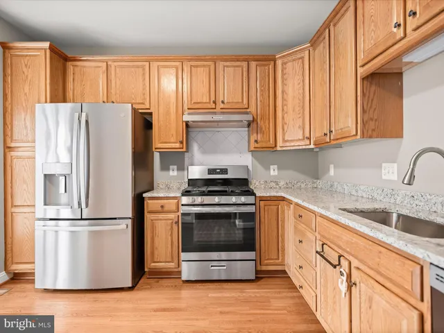 a kitchen with granite countertop a refrigerator stove and sink