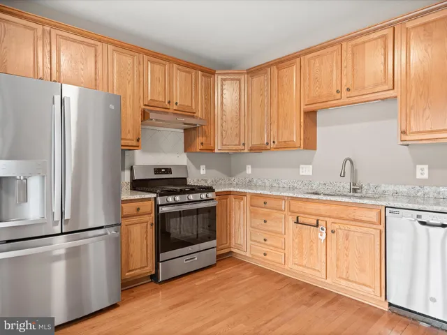 a kitchen with granite countertop stainless steel appliances a refrigerator sink and cabinets