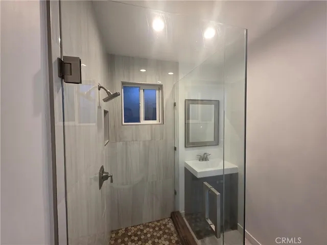 a bathroom with a sink a toilet a mirror and shower