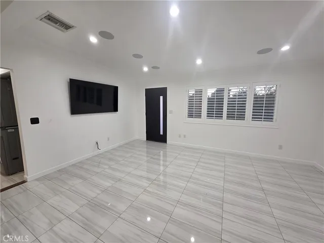 a view of an empty room with a window and a flat screen tv