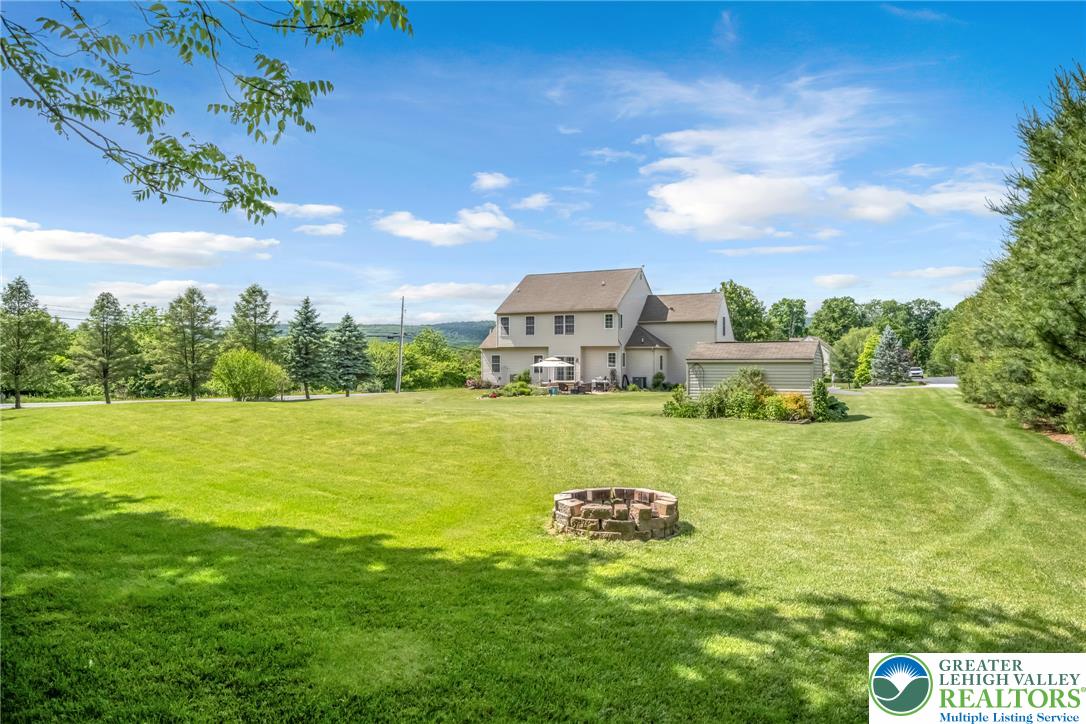 204 Bushkill Ridge Road Wind Gap, PA 18091 - Photo 7 of 48 A spacious yard with mature trees and a stone fire pit, perfect for outdoor entertaining.