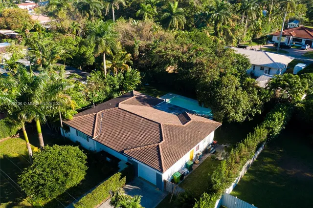 an aerial view of residential house with outdoor space and trees all around