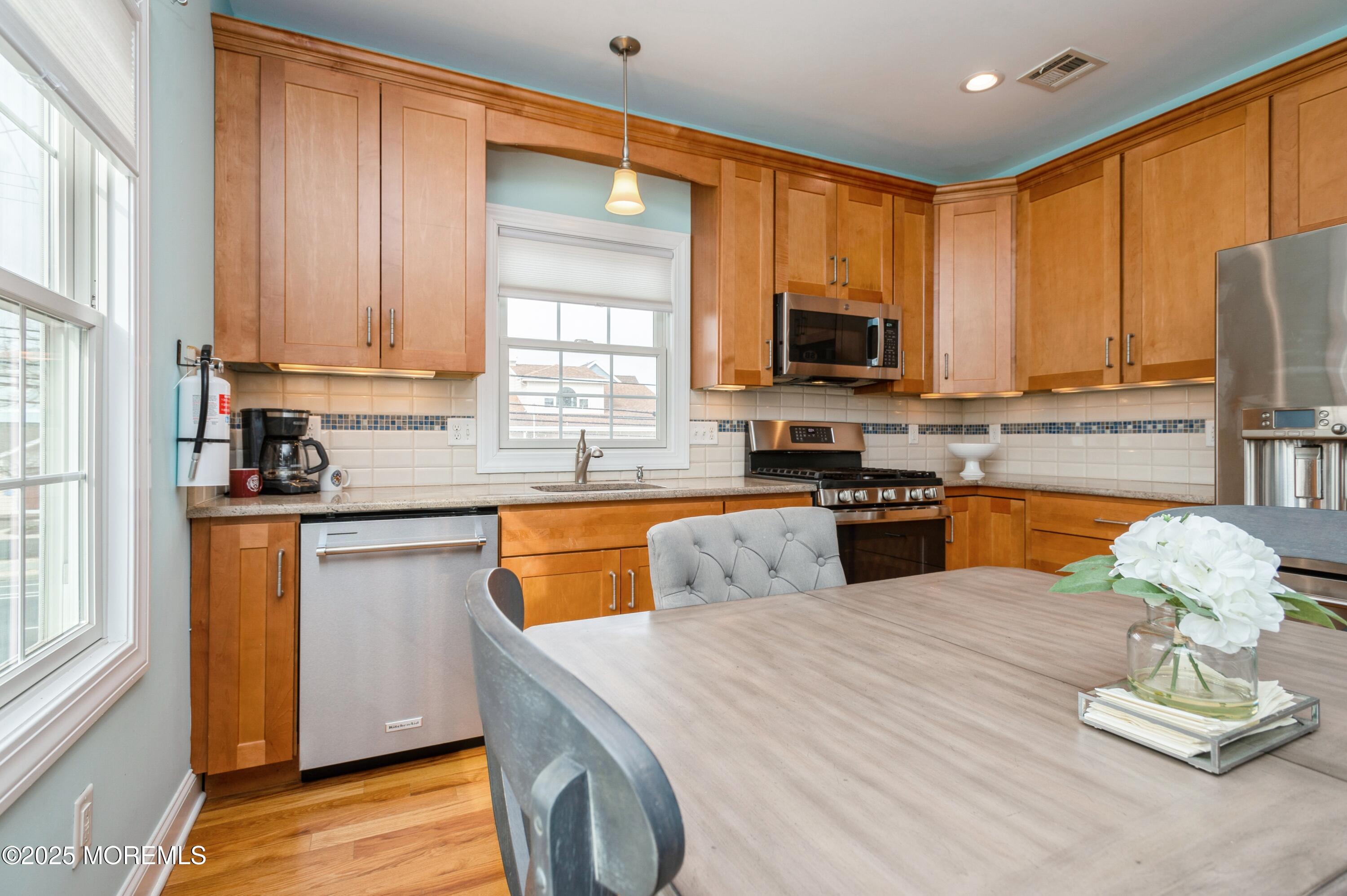143 North Bayside Road Lavallette, NJ 08735 - Photo 6 of 23 a kitchen with stainless steel appliances wooden cabinets a stove top oven a sink and dishwasher with wooden floor