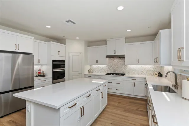 a kitchen with stainless steel appliances a sink a stove a refrigerator and cabinets