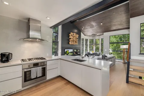 a kitchen with a stove a refrigerator and a view of living room