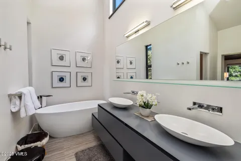 a bathroom with a white tub a sink and a mirror