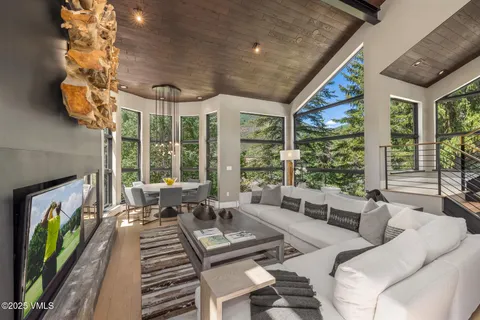 a living room with furniture floor to ceiling window and a flat screen tv