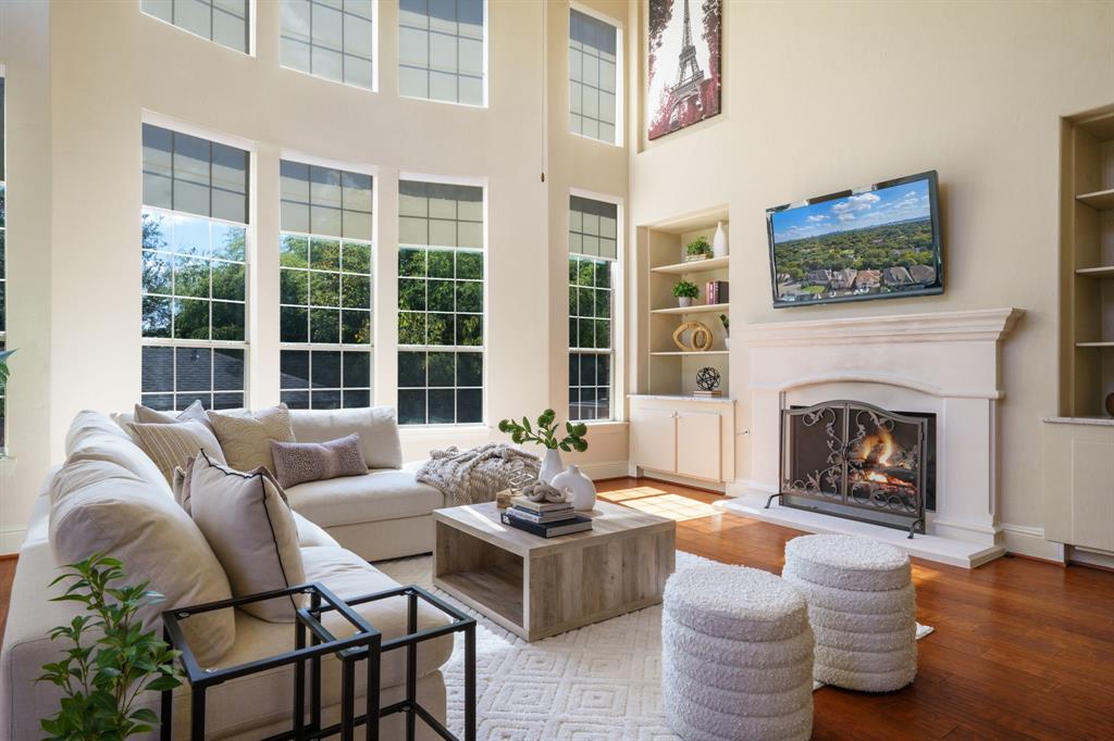 9106 Cochran Bluff Lane Dallas, TX 75220 - Photo 7 of 40 Living area with built in features, wood finished floors, a lit fireplace, and a high ceiling