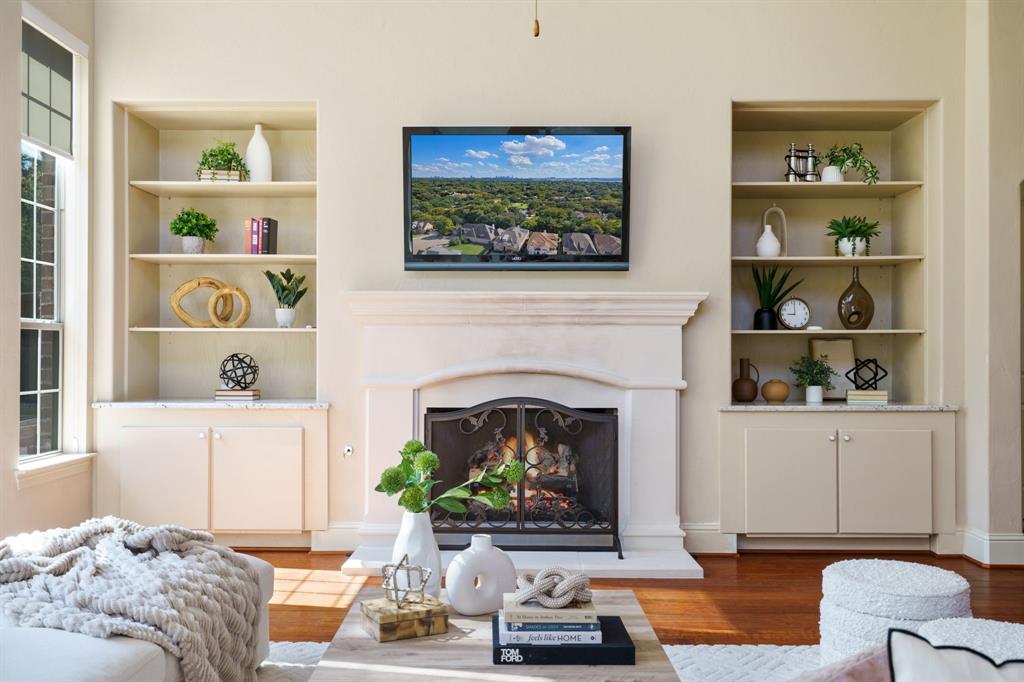9106 Cochran Bluff Lane Dallas, TX 75220 - Photo 8 of 40 Living room featuring built in shelves, a warm lit fireplace, and wood finished floors