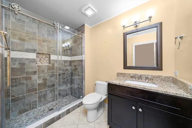 a bathroom with a granite countertop sink toilet a mirror and shower