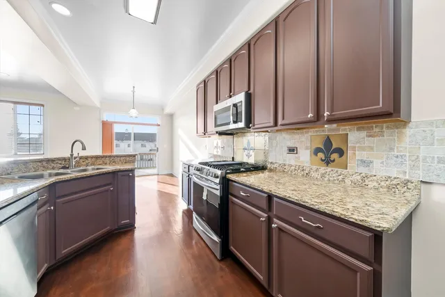 a kitchen with stainless steel appliances granite countertop a stove a sink dishwasher and cabinets with wooden floor