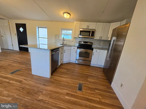 a kitchen with granite countertop a refrigerator and a stove top oven
