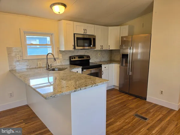 a kitchen with a sink a microwave a refrigerator and cabinets