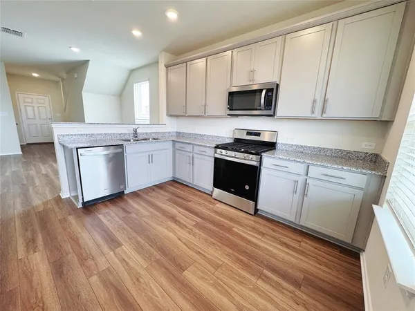 a kitchen with a sink wooden floor and stainless steel appliances