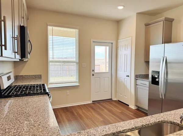 a kitchen with stainless steel appliances granite countertop a stove a sink and a microwave
