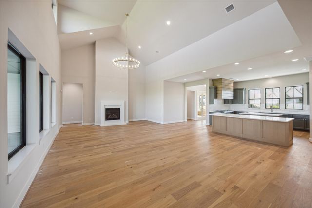 a large kitchen with a center island wooden floor stainless steel appliances and windows
