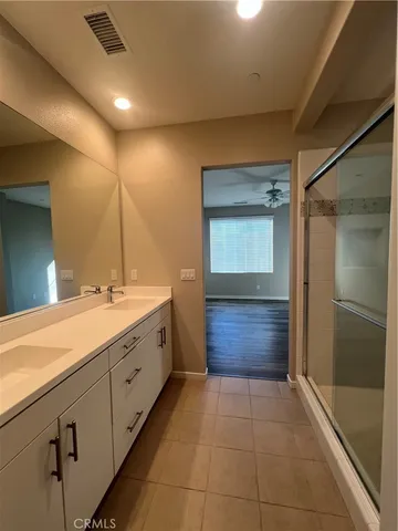 a spacious bathroom with a double vanity sink a large mirror and a shower