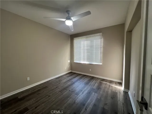 an empty room with wooden floor and a ceiling fan