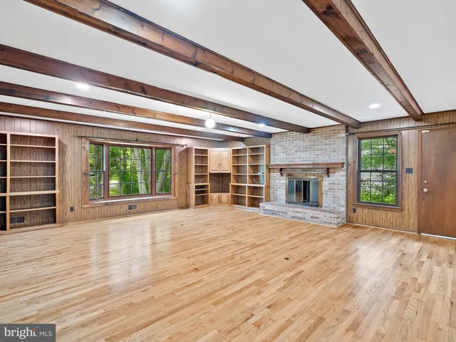a view of empty room with wooden floor and windows