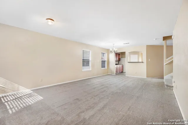 a view of empty room with kitchen and window